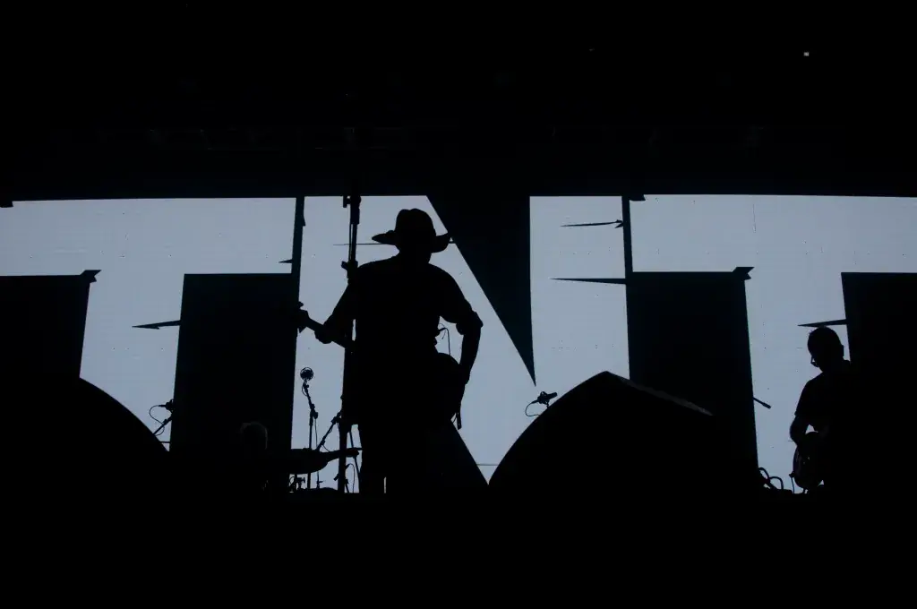 Silhueta da banda no palco diante do logo TNT